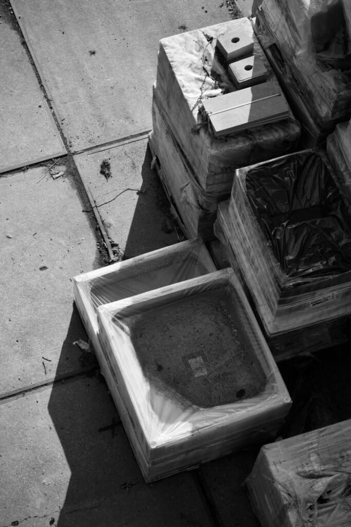 Black and white photo of stacked construction materials outdoors, showcasing industrial textures and shadows.